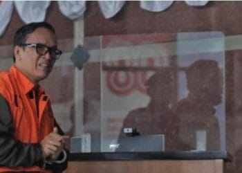 Immanuel Ebenezer alias Noel berdiri dengan rompi tahanan oranye, digiring menuju mobil tahanan KPK—latar momen emosional saat ia berharap mendapat amnesti. (Sumber: CNN Indonesia/Adhi Wicaksono)