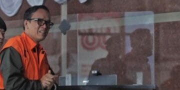 Immanuel Ebenezer alias Noel berdiri dengan rompi tahanan oranye, digiring menuju mobil tahanan KPK—latar momen emosional saat ia berharap mendapat amnesti. (Sumber: CNN Indonesia/Adhi Wicaksono)