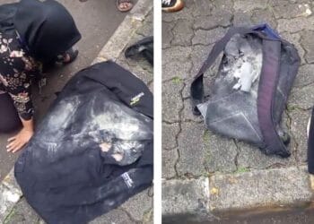 Seorang ibu tampak kesakitan sambil duduk di pinggir jalan setelah insiden demo DPR, punggungnya tampak meradang dan laptopnya rusak. Sumber: Ayobandung.com