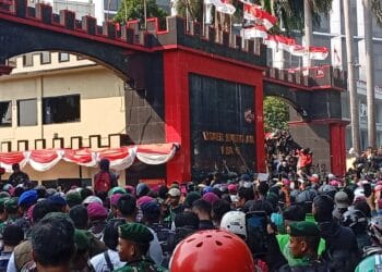 Visual memperlihatkan massa pengemudi ojol tengah melakukan aksi di depan Mako Brimob Kwitang, diselingi dengan penggunaan gas air mata oleh aparat. (Sumber: Okezone)