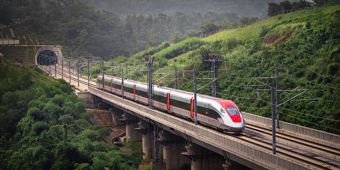 Kereta cepat Whoosh melaju di atas rel dengan latar hijau, menggambarkan momen sesaat sebelum gangguan terjadi karena layang-layang. (Sumber: detikFinance)