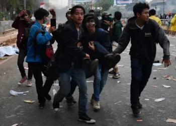 Seorang pendemo yang terluka saat aksi dibawa oleh rekannya untuk mendapat pertolongan medis  (Sumber: ADEK BERRY/AFP)