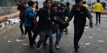 Seorang pendemo yang terluka saat aksi dibawa oleh rekannya untuk mendapat pertolongan medis  (Sumber: ADEK BERRY/AFP)