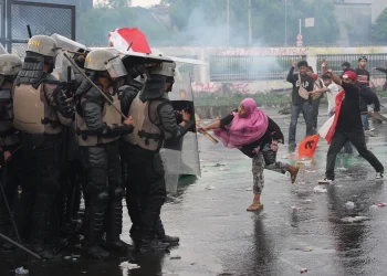 Aksi massa saat kericuhan, menunjukkan kondisi tak kondusif yang memicu kerugian bisnis—Sumber: Reuters (via Bloomberg)