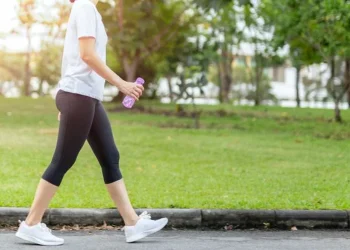 Seorang wanita berjalan kaki di area outdoor sebagai bagian dari rutinitas olahraga harian. Aktivitas sederhana ini dapat membantu membakar kalori dan menjaga kebugaran tubuh. (Sumber: Shutterstock)