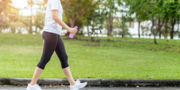 Seorang wanita berjalan kaki di area outdoor sebagai bagian dari rutinitas olahraga harian. Aktivitas sederhana ini dapat membantu membakar kalori dan menjaga kebugaran tubuh. (Sumber: Shutterstock)
