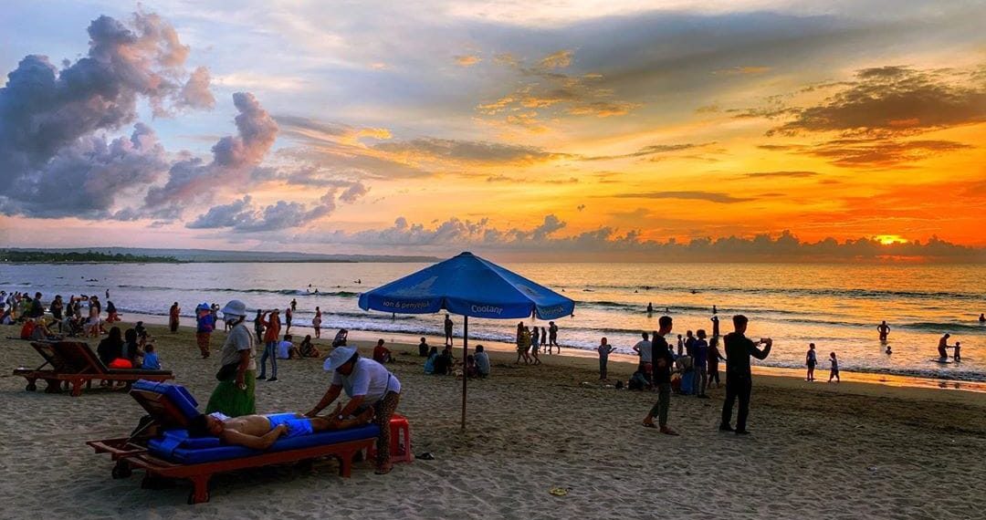 Pantai Kuta saat senja—langit jingga berpadu sempurna dengan ombak tenang dan pasir putih yang memesona. (Sumber: Tripcetera.com)