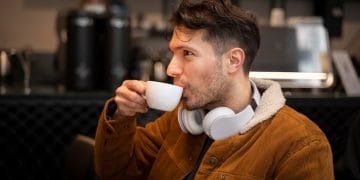 Seseorang duduk santai di kafe sambil menikmati secangkir kopi, suasana tenang mendukung relaksasi dan fokus mental. (Sumber: freepik)